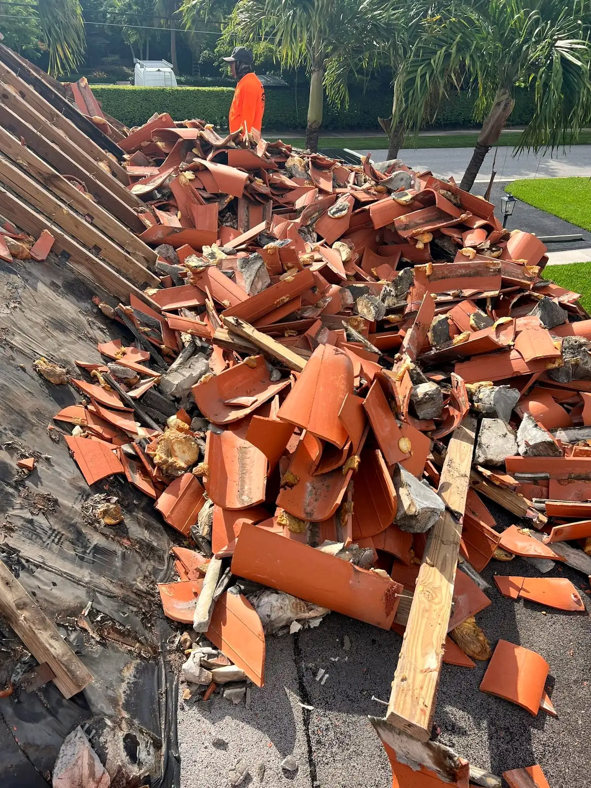 Broken clay tile and battens torn off a roof, down to the old underlayment